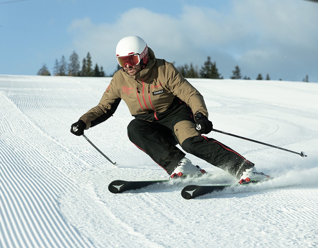Een skiër in beschermende kleding rijdt snel een besneeuwde piste af.