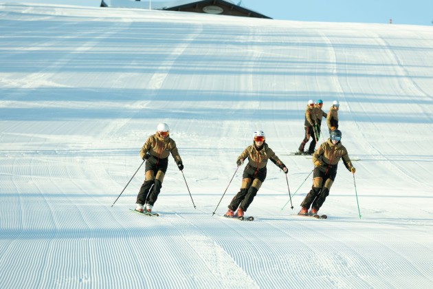 Skifahrer fahren in Formation auf einer präparierten Skipiste bergab