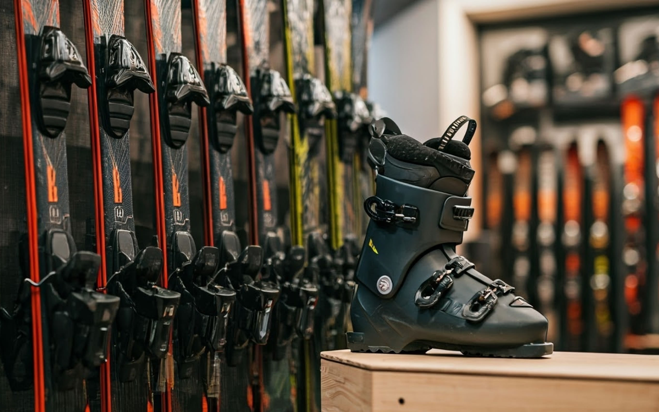 Ein schwarzer Skischuh steht vor einer Reihe von Skiern im Geschäft